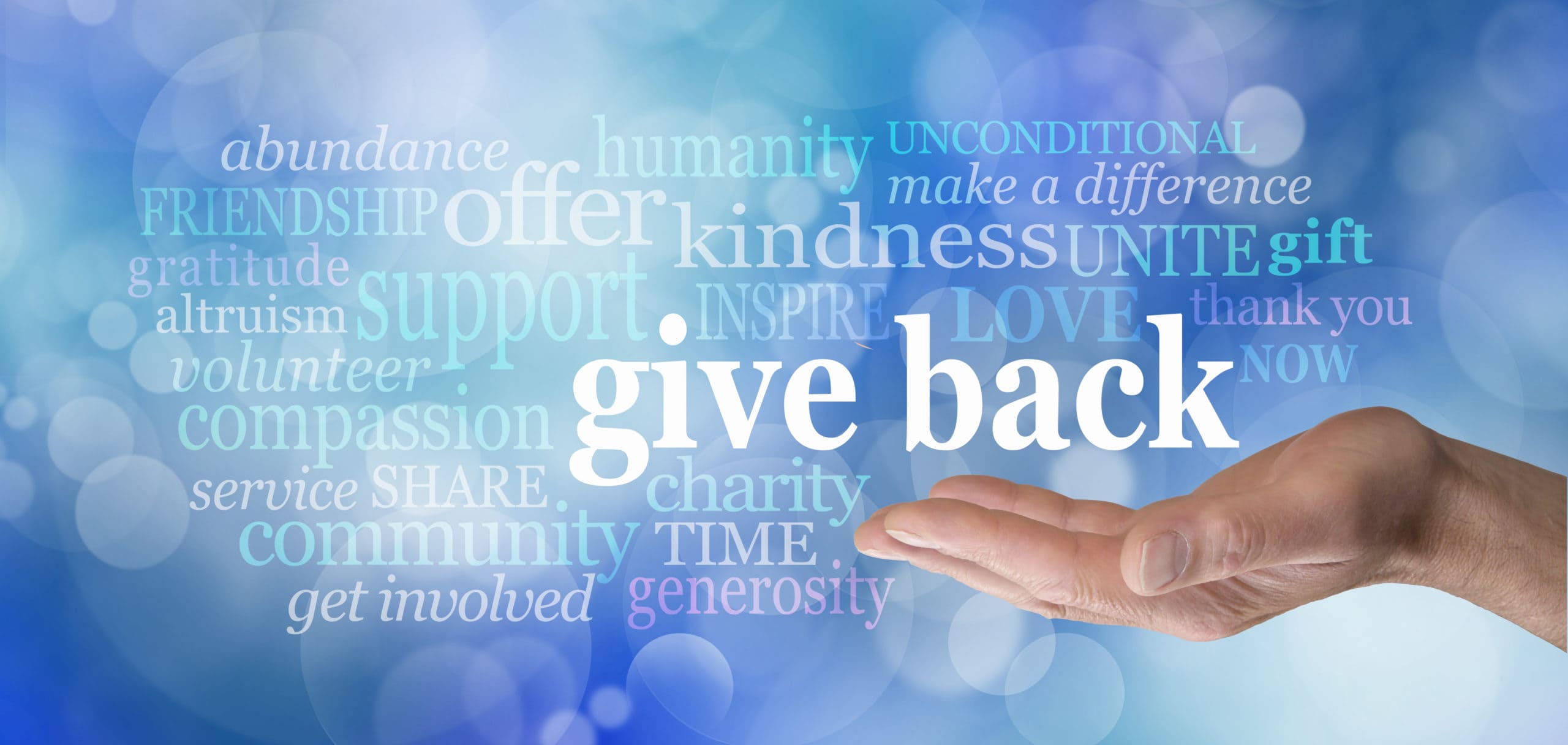 male hand with the words GIVE BACK floating above surrounded by a word cloud against a blue bokeh background